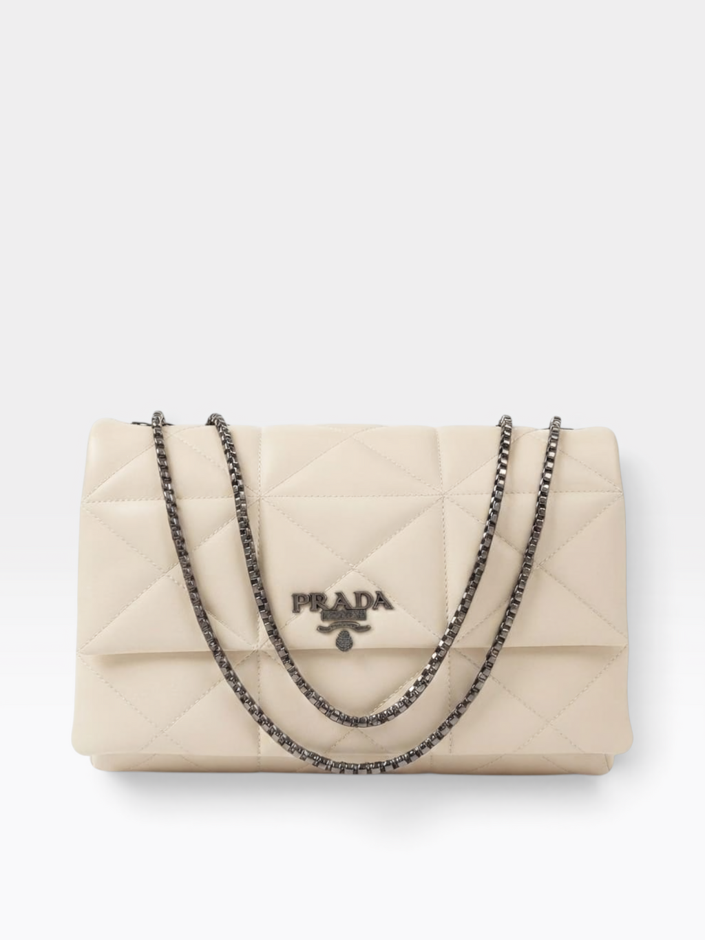 Prada quilted flap shoulder bag in off-white leather with a silver-tone chain strap and a central Prada logo plaque, shown on a light gray background.