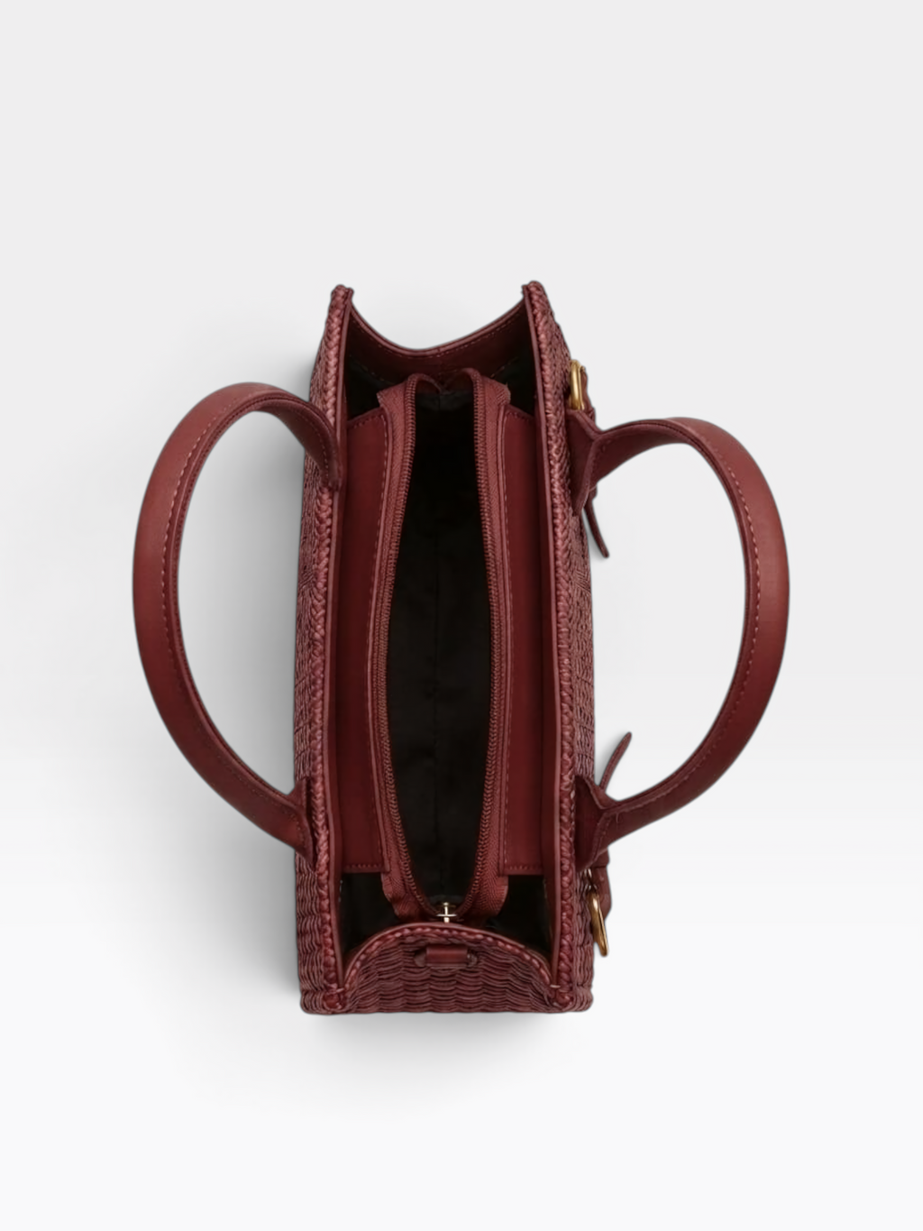 Top-down view of a structured burgundy leather handbag with a woven basket-texture base, dual top handles, and a zippered interior, shown on a light gray background.