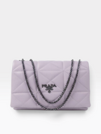 A light purple Prada quilted shoulder bag with a silver-tone chain strap and a silver-tone metal logo plaque on the front.