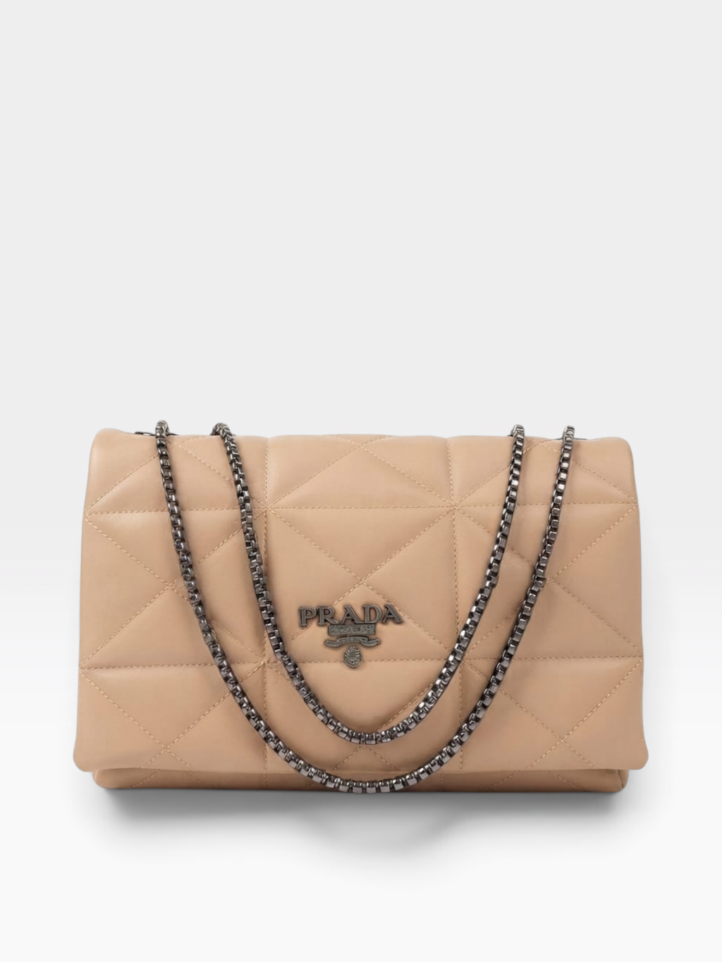 Prada quilted flap shoulder bag in beige leather with a silver-tone chain strap and a silver-tone Prada logo plaque on the front, photographed on a light gray background.