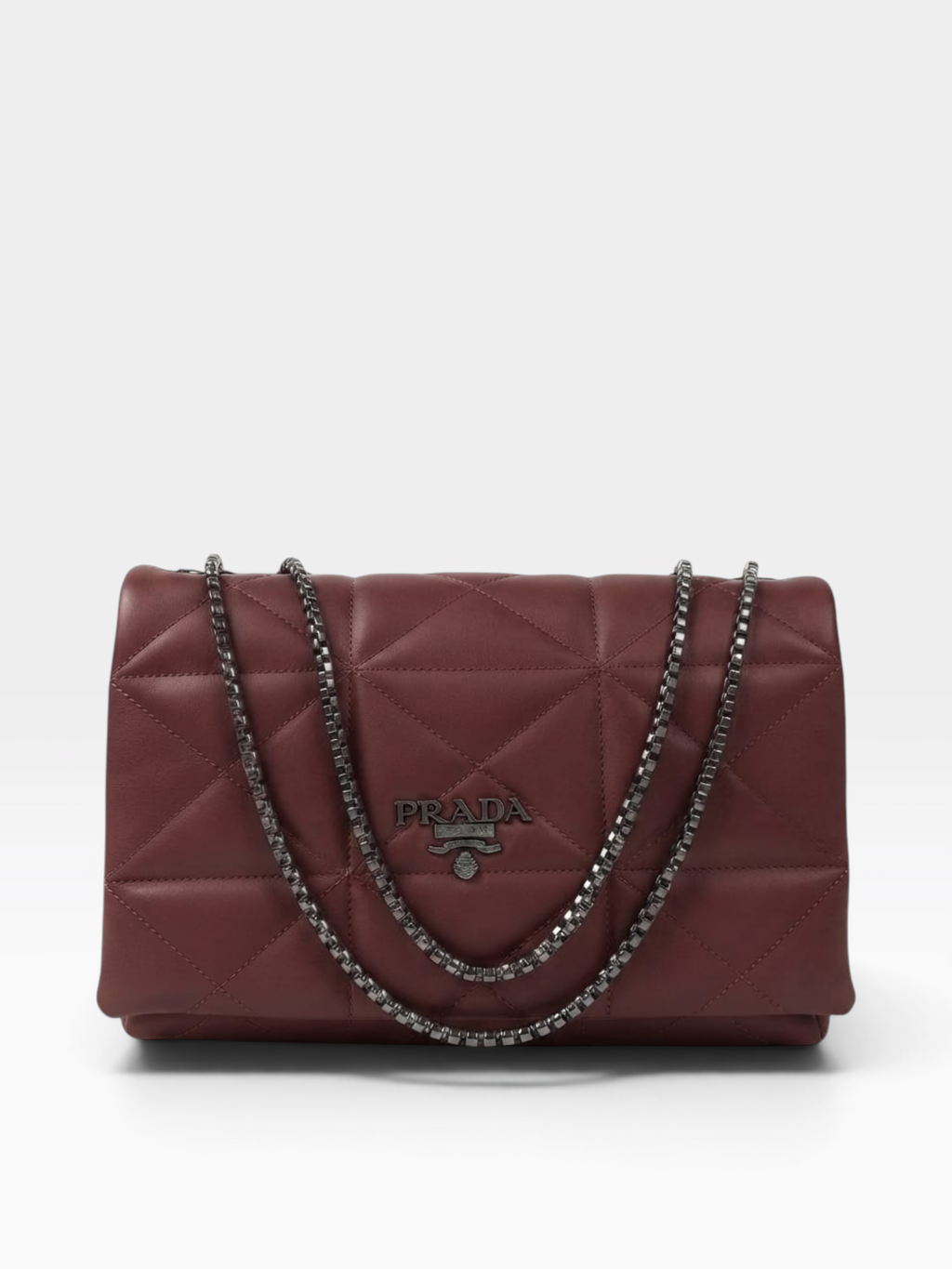 A Prada quilted leather shoulder bag in burgundy red, featuring a diamond-quilted pattern, a silver-tone chain strap, and a silver-tone metal Prada logo plaque on the front.
