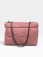 A pink quilted flap shoulder bag with a dark metal chain strap, photographed against a light gray studio background.